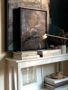 a white shelf with books and a painting on it