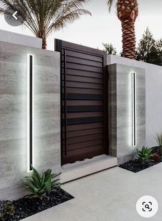 an entrance to a modern home with palm trees in the background and lights on either side