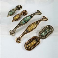 four antique door handles and knobs on a white surface with an ornate design in the middle