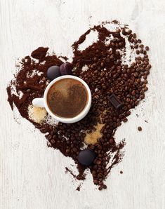 a cup of coffee and some chocolates in the shape of a heart