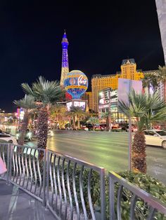 the las vegas strip at night with palm trees and neon lights in the background, as seen from across the street