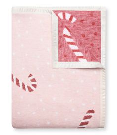 a pink blanket with red and white designs on it's side, next to a pillow