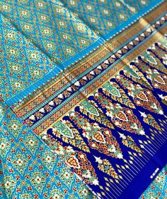 an intricately designed blue and gold shawl is shown in close up, showing the design