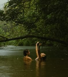 two people are in the water and one is reaching up for something