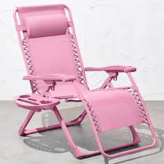 a pink reclining chair sitting on top of a cement floor next to a white wall