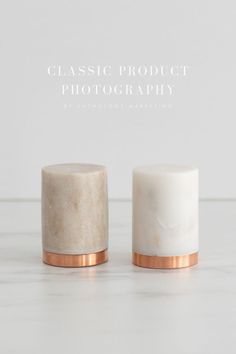 two marble jars with copper rims sitting on top of a white countertop next to each other