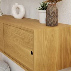 a wooden shelf with two vases sitting on it's sides next to a potted plant