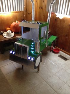 a green truck with lights on sitting in the middle of a room next to a window