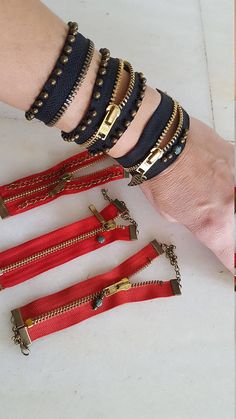 four different types of bracelets with gold and red zippers on each one wrist