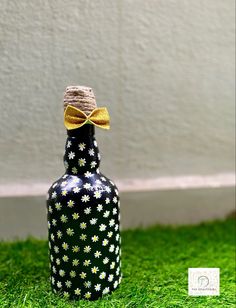 a black and white bottle with a yellow bow on it sitting in the green grass