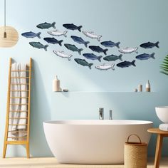 a bath tub sitting next to a wall with many fish on it's side