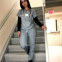 a woman in scrubs is walking down the stairs with her hand on her hip