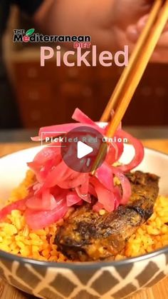 a bowl filled with rice and meat next to chopsticks