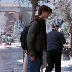 two men standing next to each other on a sidewalk