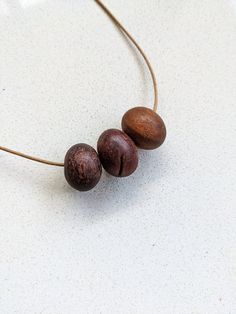 three wooden beads are hanging from a leather cord on a white counter top, with one bead in the middle