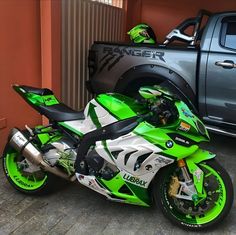 a green and white motorcycle parked next to a truck