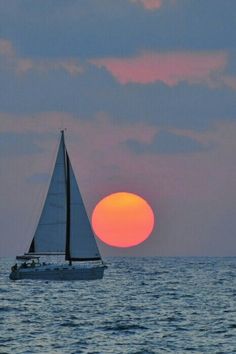 a sailboat sailing in the ocean at sunset