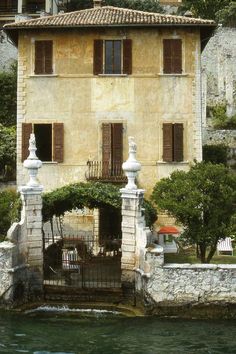 an old house with stone walls next to the water