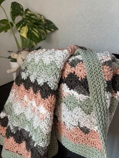 a crocheted blanket sitting on top of a table next to a potted plant