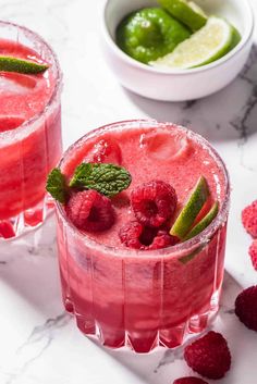 two glasses filled with raspberry margaritas and mint garnish