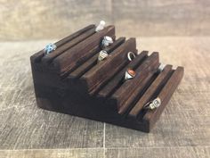 three rings are sitting on top of a wooden holder that is made out of wood