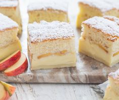 several pieces of cake sitting on top of a wooden cutting board next to an apple