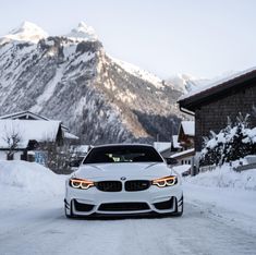 a white car parked on the side of a snow covered road in front of a mountain