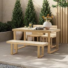 a wooden table with two benches next to some potted plants on the side walk