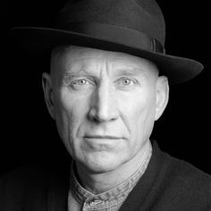 a black and white photo of a man wearing a hat with his eyes wide open