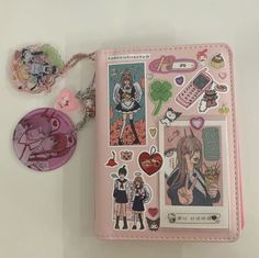 a pink book with some stickers on it and a keychain attached to it