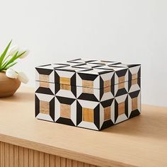 a wooden box sitting on top of a table next to a vase with flowers in it