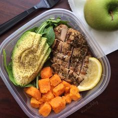 a plastic container filled with meat and veggies on top of a wooden table