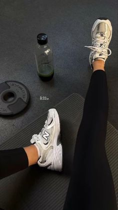 a person is sitting on a mat with their feet propped up next to a bottle of water