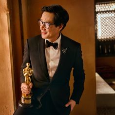 a man in a tuxedo holding an oscar statue