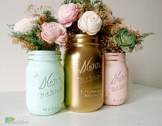 three pastel colored mason jars with flowers in them are sitting on a table next to each other