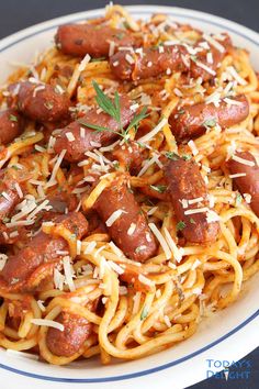 spaghetti with sausage and parmesan cheese in a white bowl on a black table