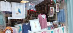 there are many items on display in the shop window, including clothes and framed pictures