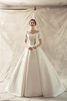 a woman in a white wedding dress posing for the camera with her hands on her hips