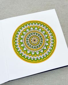 a card with an image of a flower in the middle and green, yellow and white designs on it