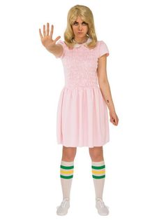 a woman wearing a pink dress and green striped socks with her hand up in the air