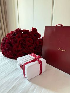 a large bouquet of red roses sitting next to a gift box