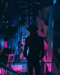 a man standing on top of a balcony next to a railing in the city at night