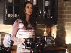 a woman standing in a kitchen holding a coffee pot