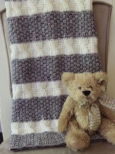 a teddy bear sitting next to a crocheted blanket