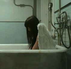 a woman with angel wings sitting in a bathtub