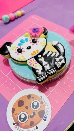 a cookie decorated like a cat on top of a table next to a sticker