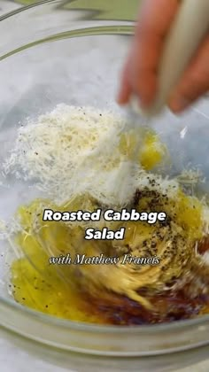 someone mixing ingredients in a glass bowl with the words roasted cabbage salad written below it