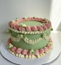 a three layer cake decorated with pink, green and white icing on a plate