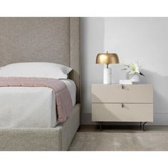 a white bed sitting next to a night stand with a lamp on top of it