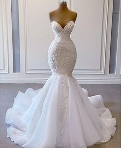 a wedding dress on display in front of a white wall with a mannequin